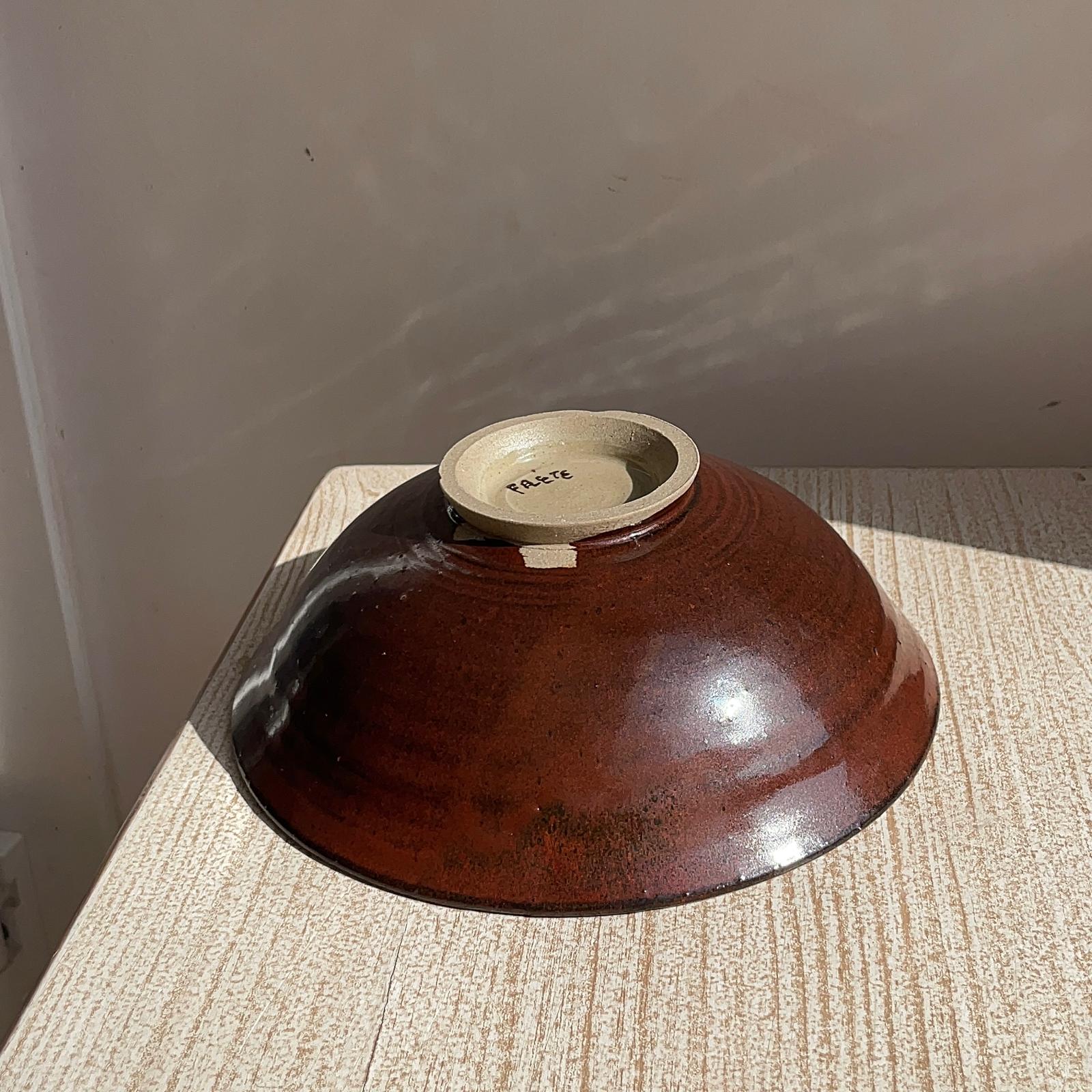 red ceramic bowl on a textured surface with a plain background
