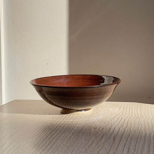 red ceramic bowl on a light wooden surface with a neutral background
