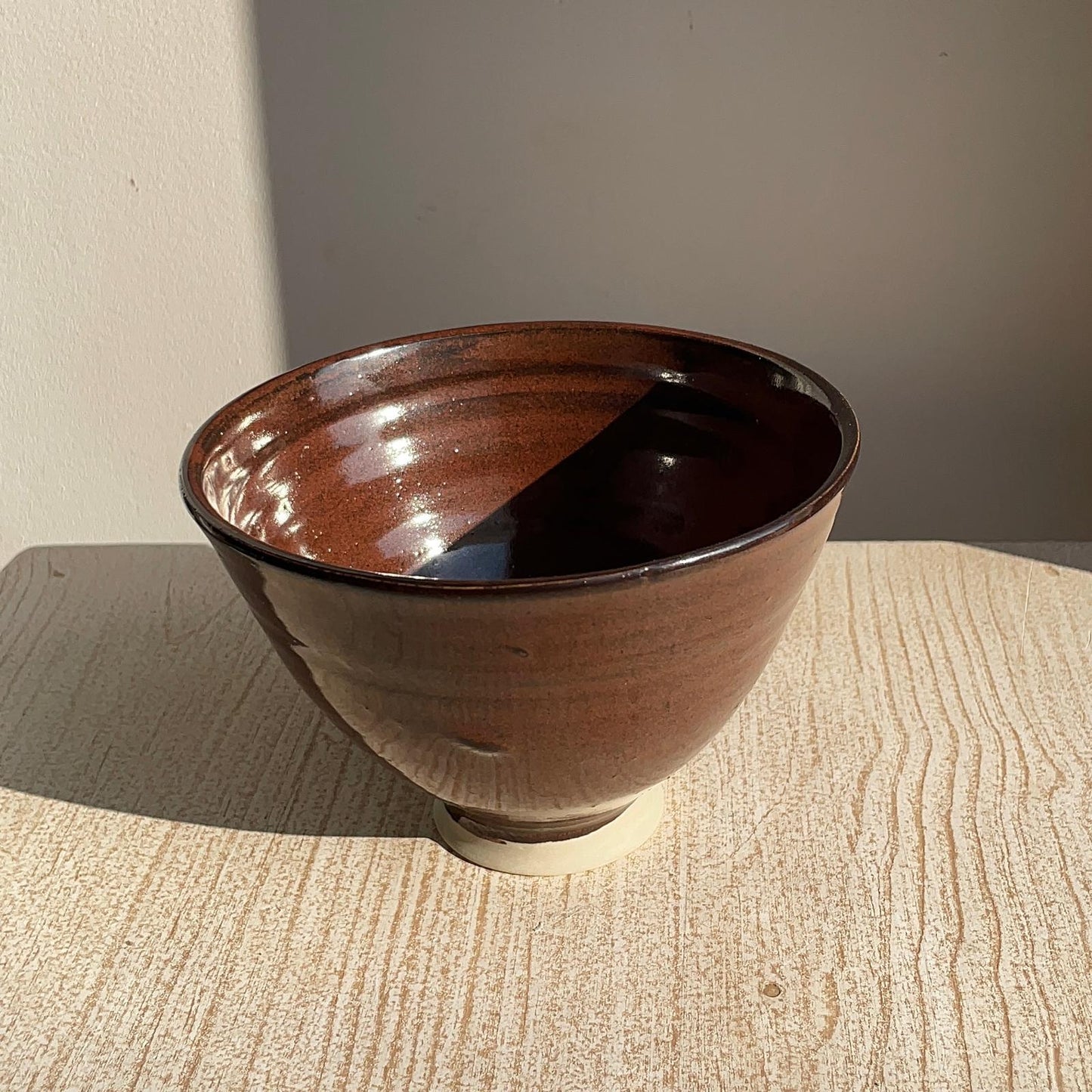 red ceramic bowl on a textured surface with a neutral background