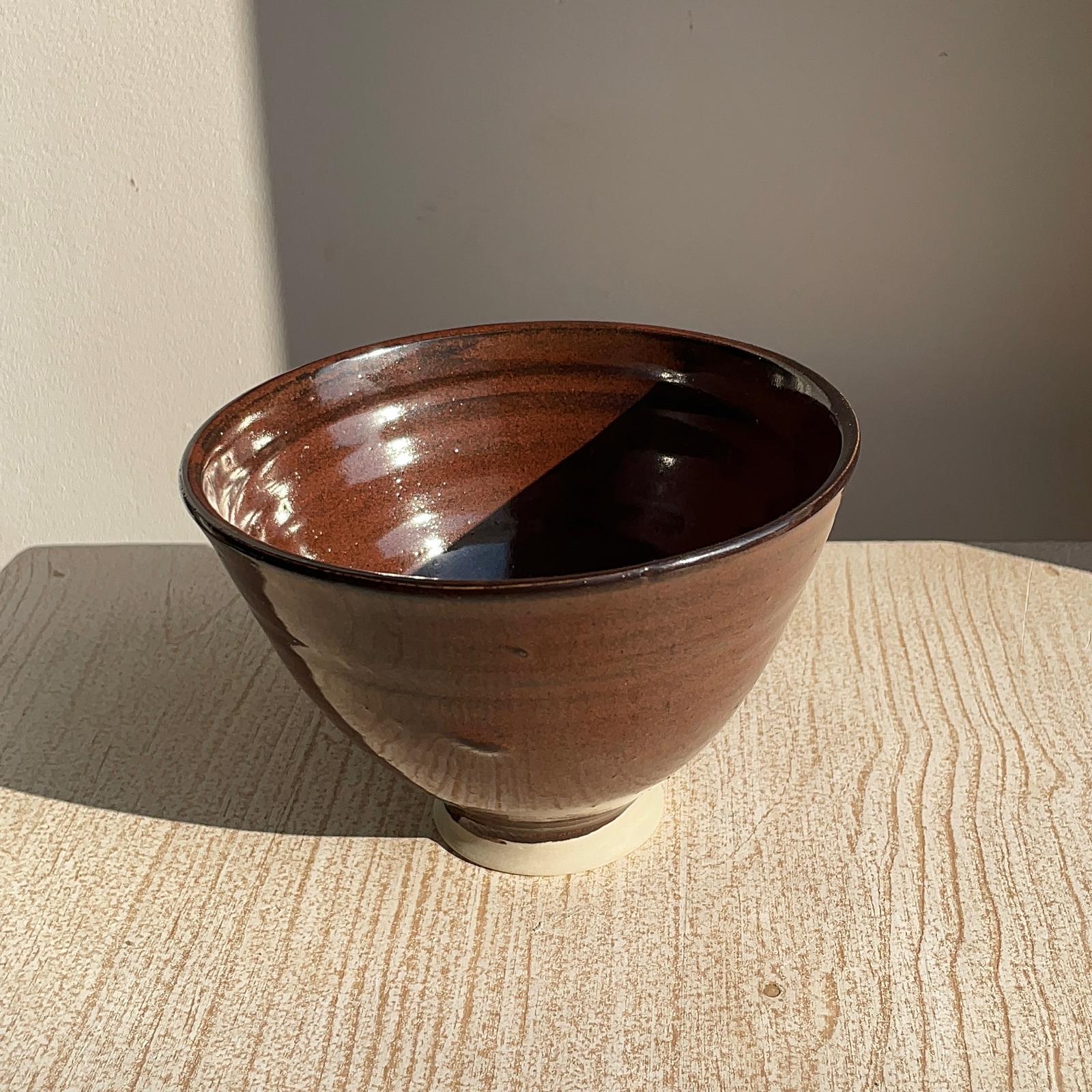 red ceramic bowl on a textured surface with a neutral background