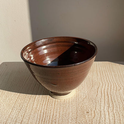 red ceramic bowl on a textured surface with a neutral background