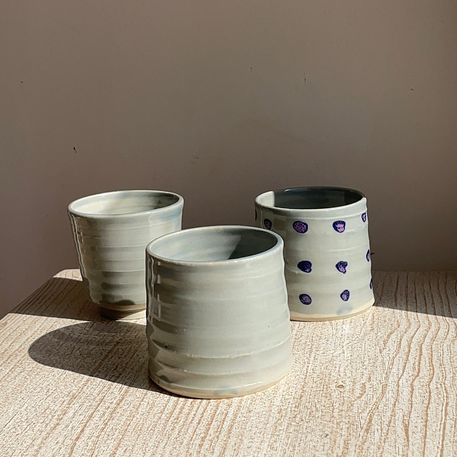 Three ceramic cups on a wooden surface with a neutral background