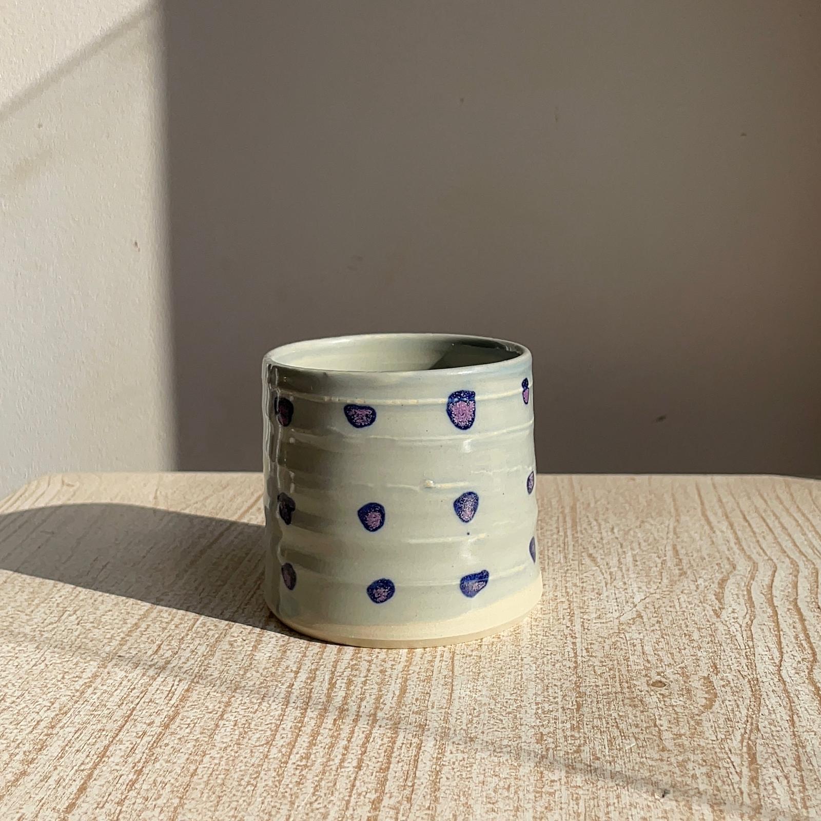 Ceramic cup with purple dots on a wooden surface