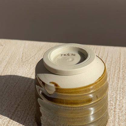caramel ceramic cup on a textured surface with a brown background