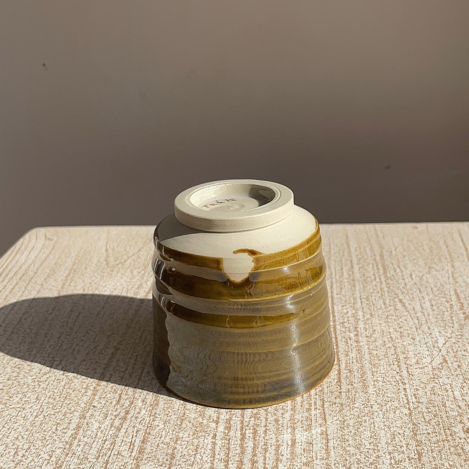 caramel ceramic cup on a textured surface with a brown background