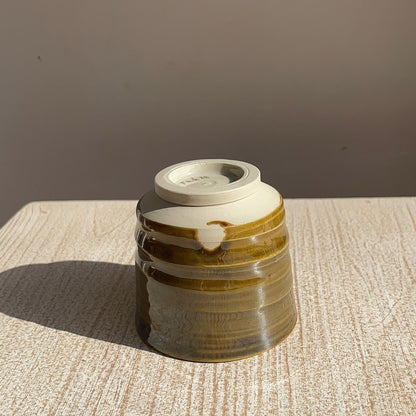 caramel ceramic cup on a textured surface with a brown background