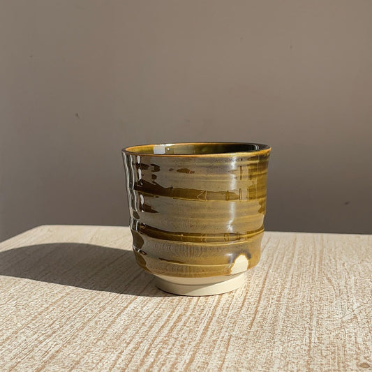 caramel ceramic cup on a textured surface with a brown background