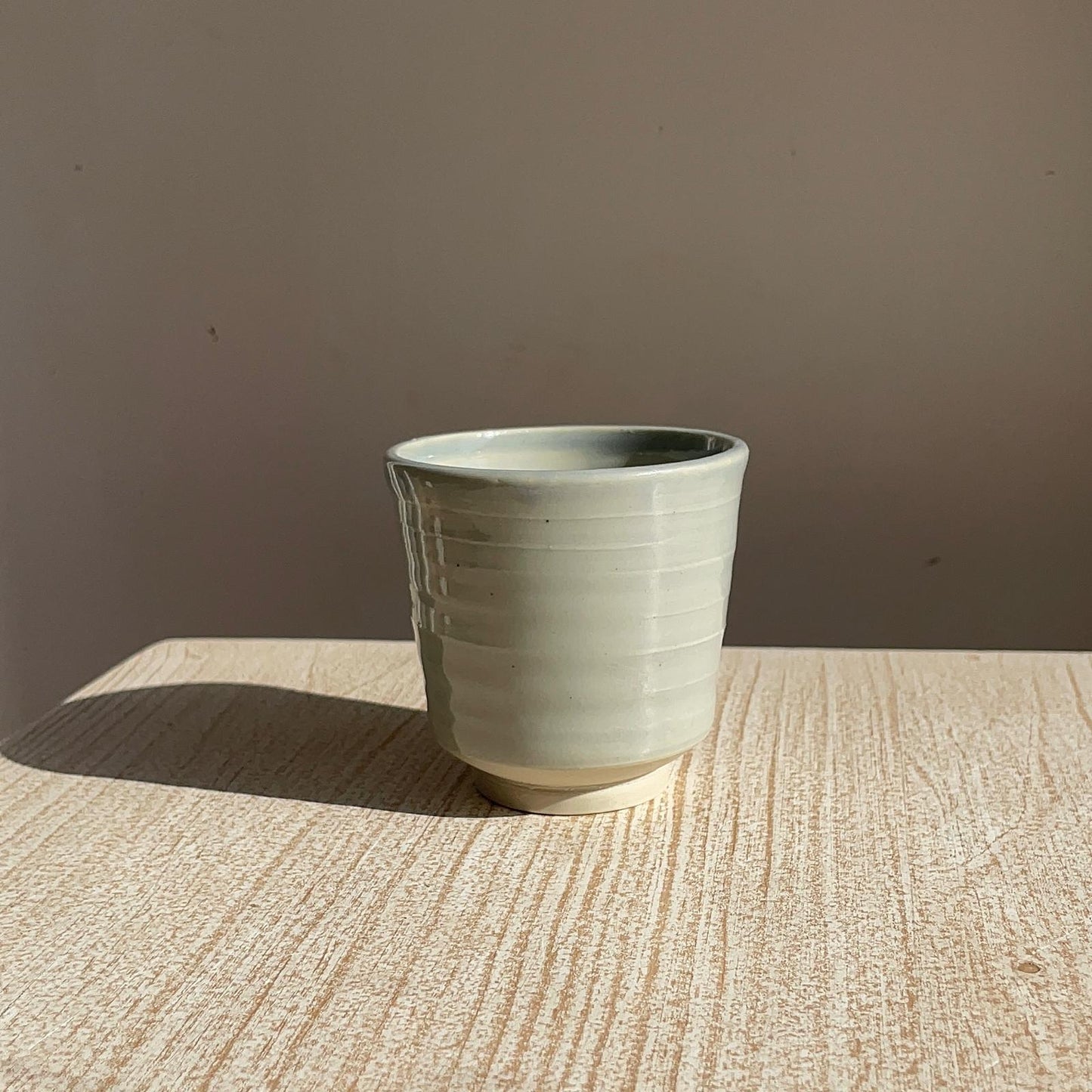 pale blue ceramic cup on a textured surface with a brown background