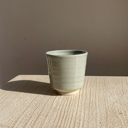 pale blue ceramic cup on a textured surface with a brown background