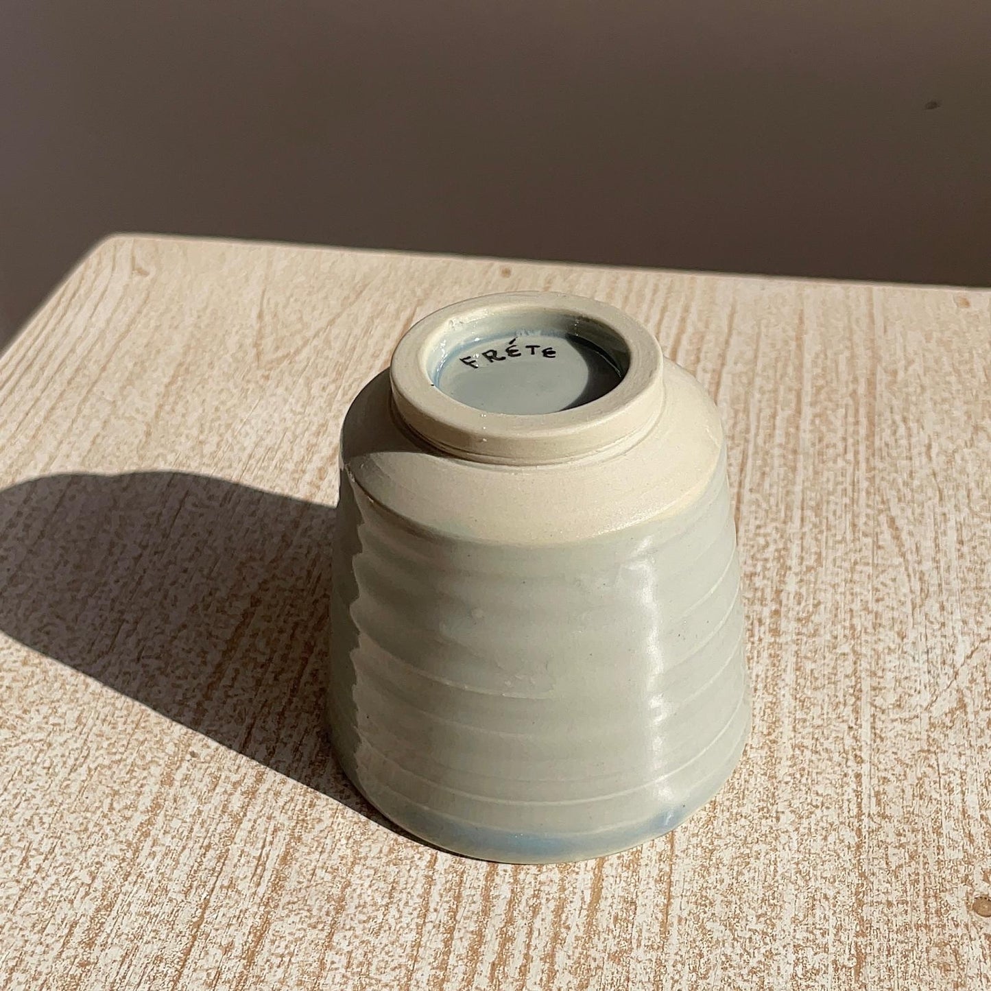 pale blue ceramic cup on a textured surface with a brown background