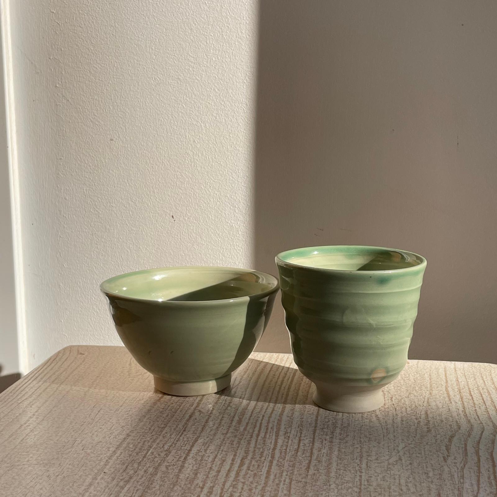 the bowl and a cup on a textured surface with a neutral background