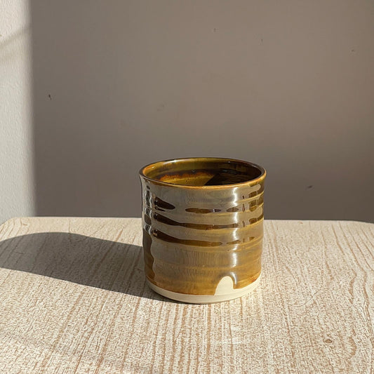 Brown ceramic cup on a textured surface with a neutral background