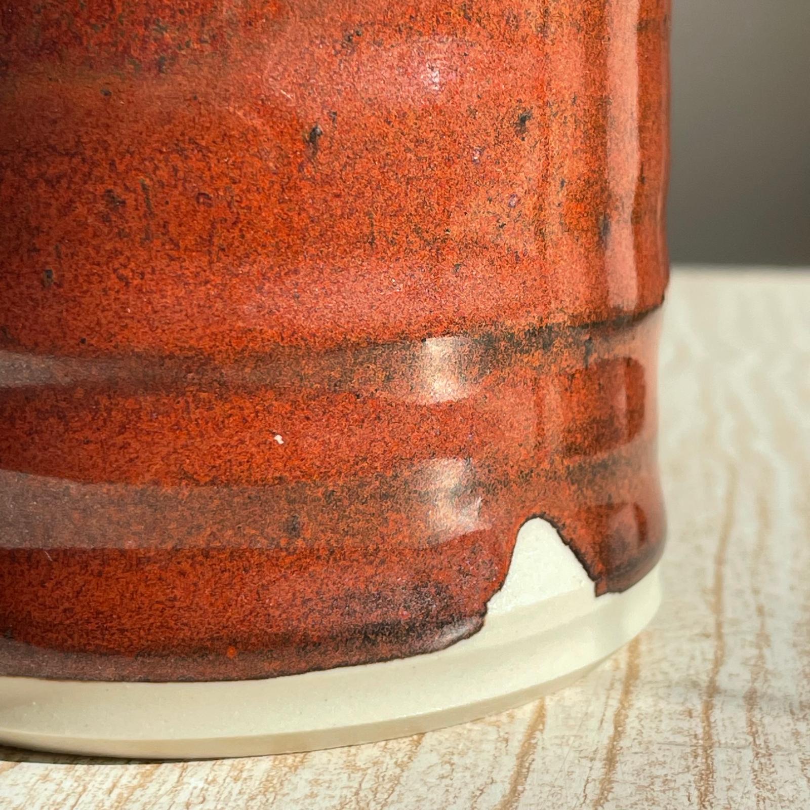 Close-up of a red ceramic cup on a wooden surface