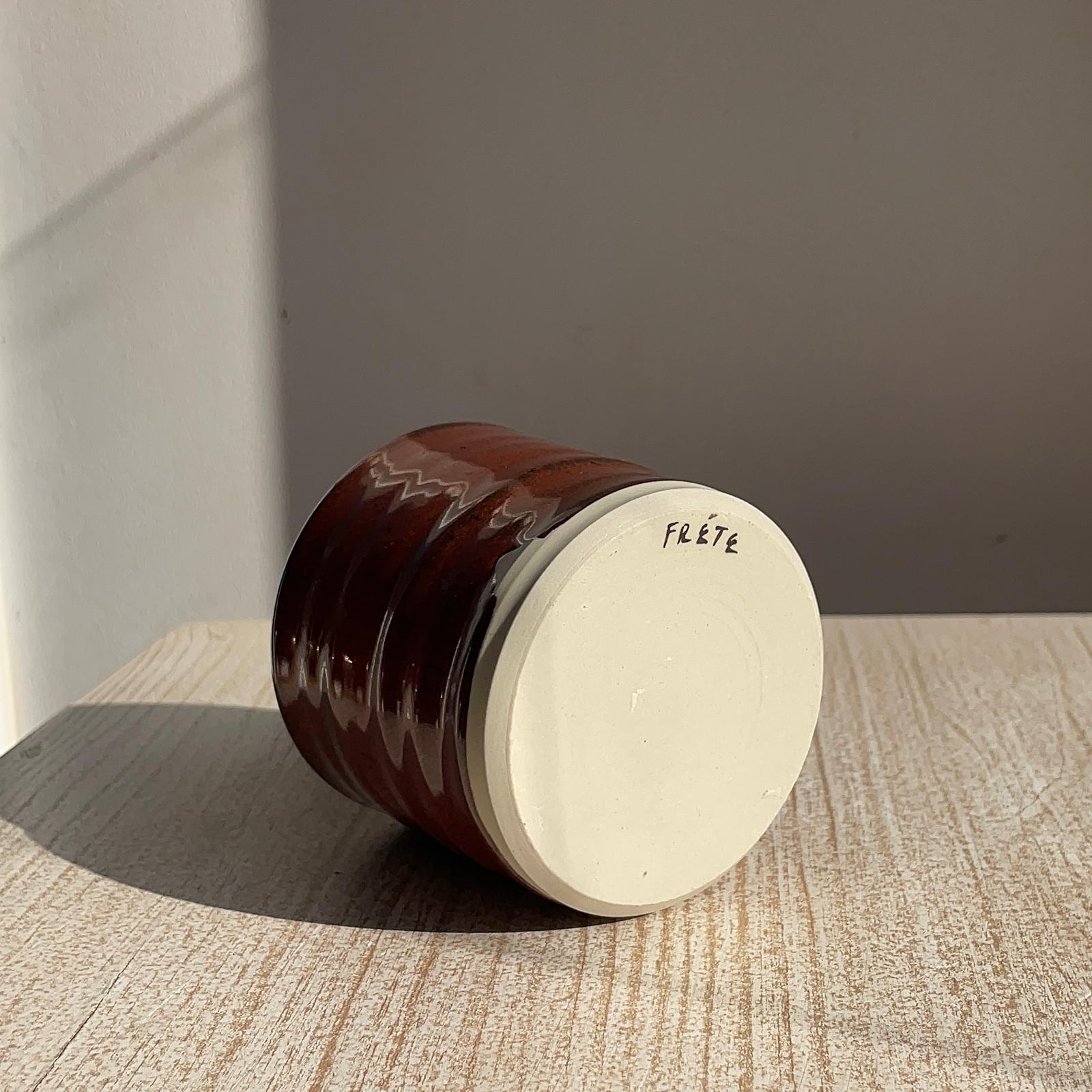 red cup with 'Frete' branding on a wooden surface