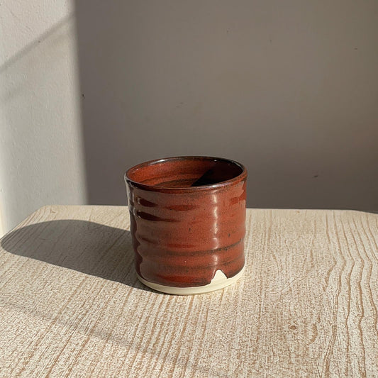 red ceramic cup on a textured surface with a neutral background