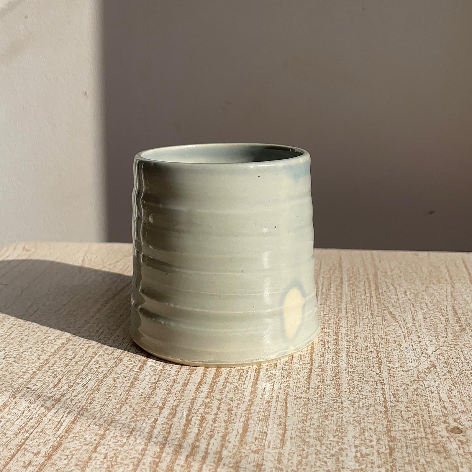 blue ceramic cup on a wooden surface with a neutral background