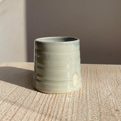 blue ceramic cup on a wooden surface with a neutral background
