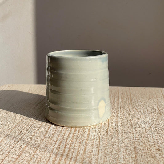 blue ceramic cup on a wooden surface with a neutral background
