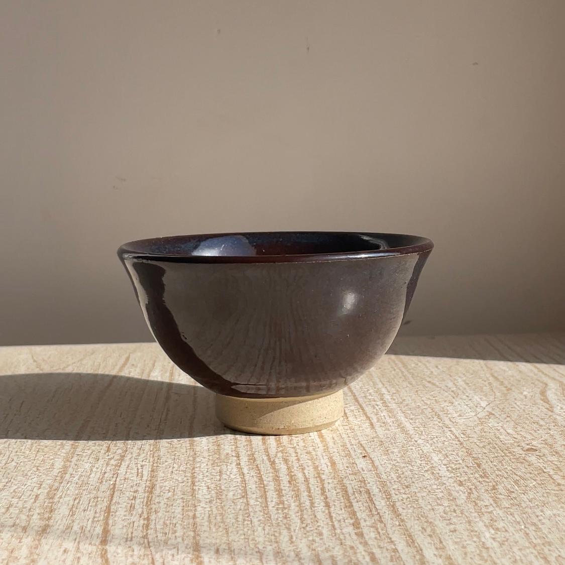 Ceramic bowl with a dark glaze on a textured surface