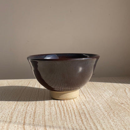 Ceramic bowl with a dark glaze on a textured surface